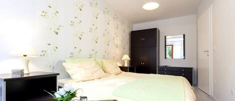 A modern bedroom with a bed, bedside tables, a wardrobe, and a tray with a cup and glass.