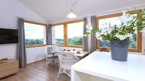 A modern room with a dining table, wicker chairs, a large potted plant, and a flat-screen TV mounted on the wall. - "BUENA VISTA" 55m2, south-facing balcony, fenced, 5ft. beach, suitable for children, Rovinj (Rovinj)