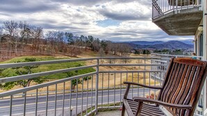 Ein Balkon mit Blick auf eine Straße, Bäume und Berge.
