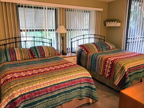 A bedroom with two beds, a nightstand, a lamp, and a window with blinds. - Resort style living in corner unit building A! Closest to pool and grill! (Bonita Springs)