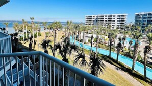 A resort with a pool area, palm trees, and a view of the ocean. - Heron 408 — 3BR Bayside Condo at Destin West with Heated Pool (Fort Walton Beach)