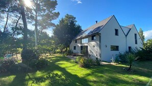A two-story house with a sloped roof, solar panels, and a well-maintained lawn. - Contemporary house and its landscaped garden in Carnac (Carnac)