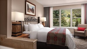 A hotel room with a bed, a nightstand, a lamp, a chair, a window with a view of trees, and a painting on the wall. - Unit inside a Luxury resort + heated pool (Vail)