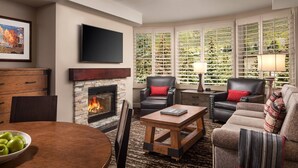 A living room with a fireplace, leather chairs, a coffee table, and a TV mounted on the wall. - Unit inside a Luxury resort + heated pool (Vail)