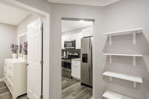 A modern kitchen with white cabinets, stainless steel appliances, and a wooden floor. - Waters Avenue Unit B (Tampa)