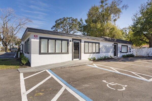 A small building with a white exterior and black-framed windows, a parking lot with marked handicapped spaces, and a sign indicating a business or office use. - Waters Avenue Unit B (Tampa)