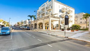 A multi-story hotel with balconies, a covered entrance, and a clear blue sky. - Appartamento Corso Italia II by Barbarhouse (Gallipoli)