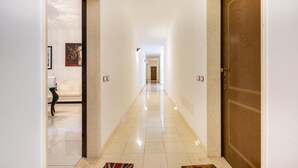 A hallway with a wooden door on the right, a light-colored floor, and a framed picture on the left wall. - Appartamento Corso Italia II by Barbarhouse (Gallipoli)