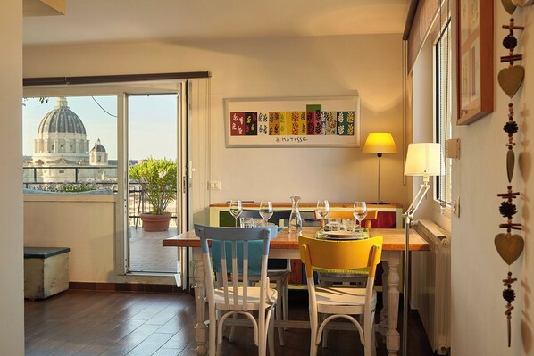 A dining area with a table set for two, a view of a dome building, and a framed artwork on the wall. - Rooftop Loft Vatican view & secure parking (a.14) (Roma)