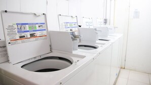 A row of white, modern, self-cleaning toilets with instructional posters on the front. - Tangerine Sunsets Seville (Nassau)