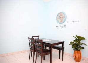A dining area with a table and chairs, a wall clock, and a potted plant. - Tangerine Sunsets Seville (Nassau)