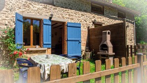 A stone building with blue shutters, a wooden table with a tablecloth, and a brick oven. - Cottage - Peaceful and nature (Cieux)