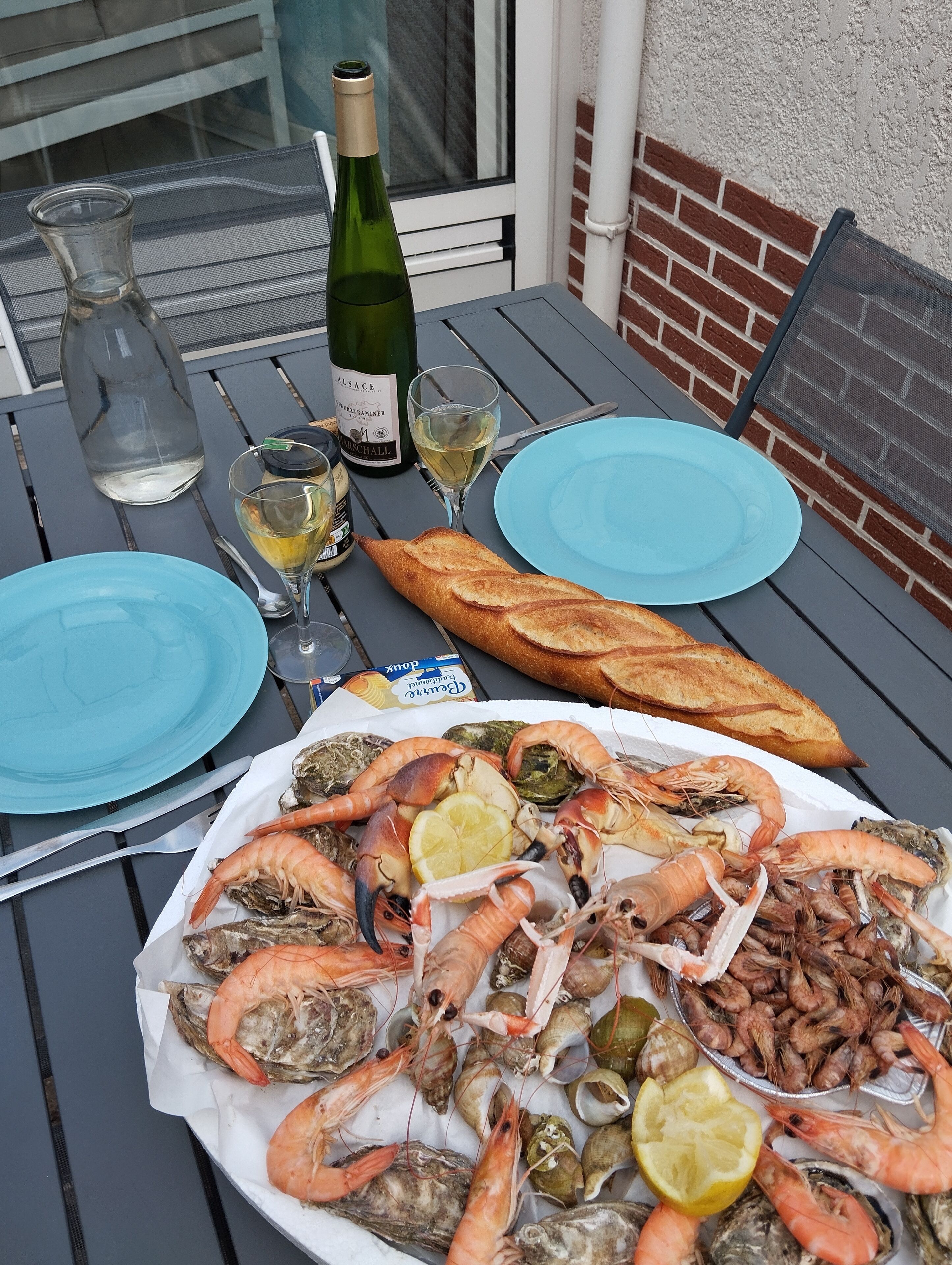 Una mesa dispuesta con mariscos, una botella de vino y platos azules.