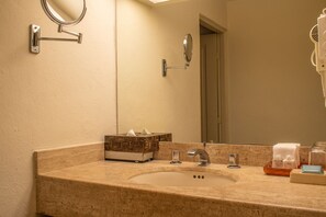 A bathroom with a sink, mirror, and toiletries.