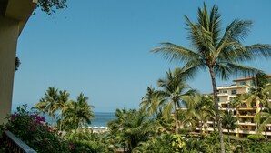 A resort with a view of the ocean, palm trees, and a pool area. - Beautiful Studio with balcony inside resort (Puerto Vallarta)