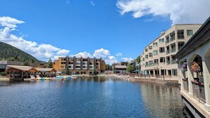 A waterfront hotel with multiple buildings, a dock with boats, and a clear blue sky. - Lakeside 1476 (Keystone)