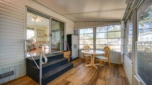 A cozy room with a wooden floor, a round table with two chairs, a staircase leading to another room, and large windows offering a view of the outside. - Relaxing Home Pool Access and Screened-In Porch! (Sarasota)
