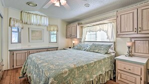 A bedroom with a large bed, wooden cabinets, a window with curtains, and a ceiling fan. - Relaxing Home Pool Access and Screened-In Porch! (Sarasota)