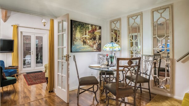 A dining area with a glass table, chairs, and a painting on the wall. - Mirrored Reflections (London)