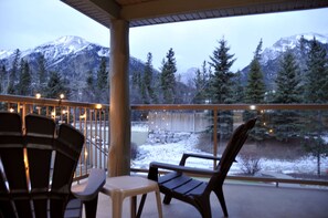 A balcony with chairs and a table, overlooking a snowy landscape with trees and mountains. - ❤Mnt. View King Bed Room| Private Balcony| No Kitchen| Indoor Parking (Canmore)