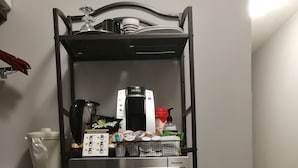 Een kleine keuken met een inbouwmagnetron, oven en koffiezetapparaat op een plank.