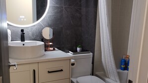 Een moderne badkamer met een ronde spiegel, een wastafel, een toilet en een douchehoek.