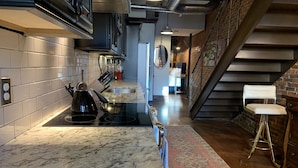 Een moderne keuken met een marmeren aanrecht, roestvrijstalen apparatuur en een vloerkleed met een patroon.