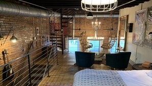 Een knus hotelkamer met een bakstenen muur, een groot bed, een houten vloer en uitzicht op een stadsgezicht.