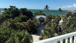 A coastal view with a sandy beach, palm trees, and a clear blue sky. - Coconut Castaway | Ocean Views, Golf Cart & Club Pool (Upper Captiva)