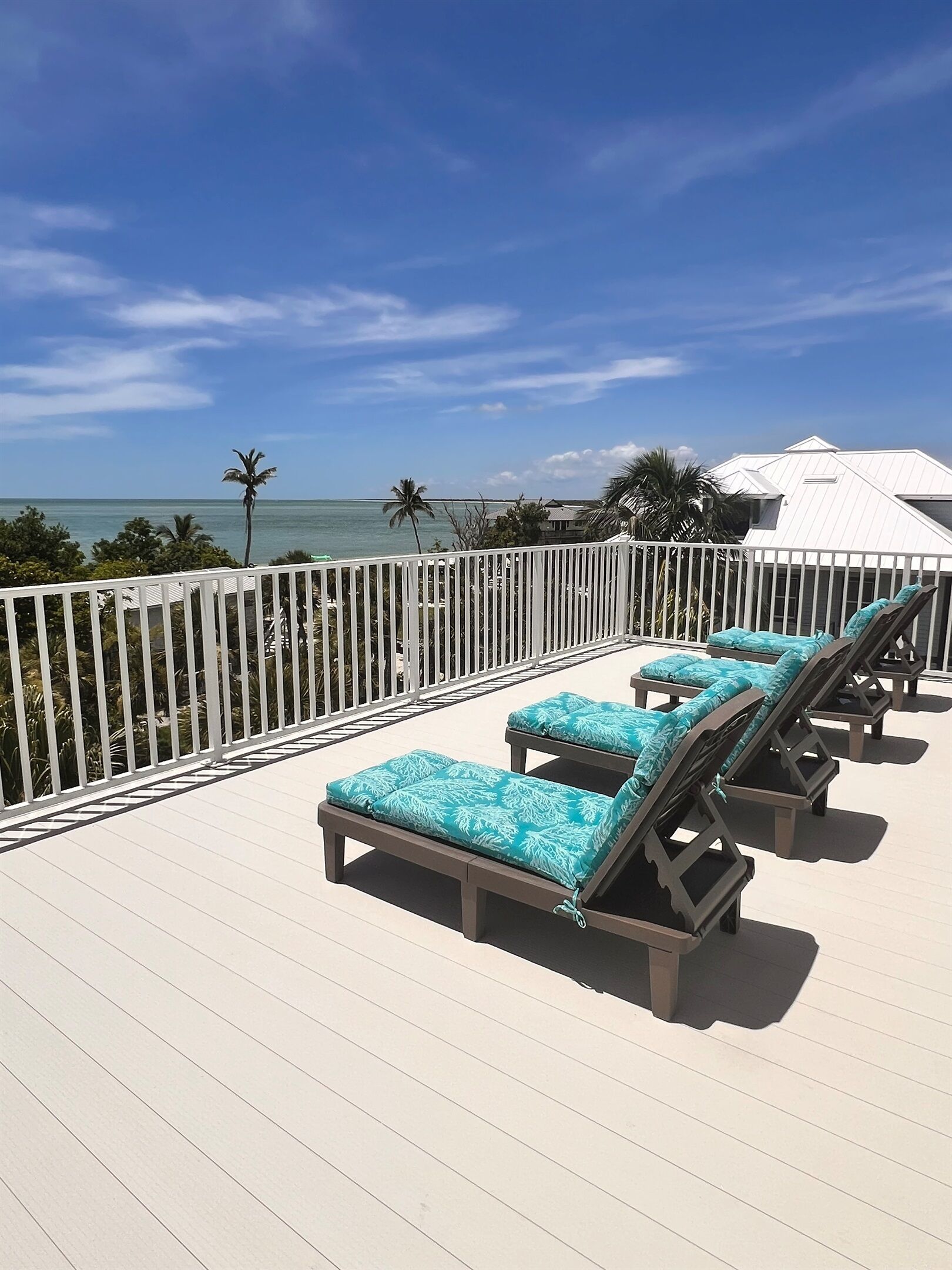 Um terraço com espreguiçadeiras e guarda-corpo com vista para uma praia.