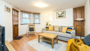 Ein Wohnzimmer mit einer Couch, einem Couchtisch, einem Fernseher und einer Holztür.