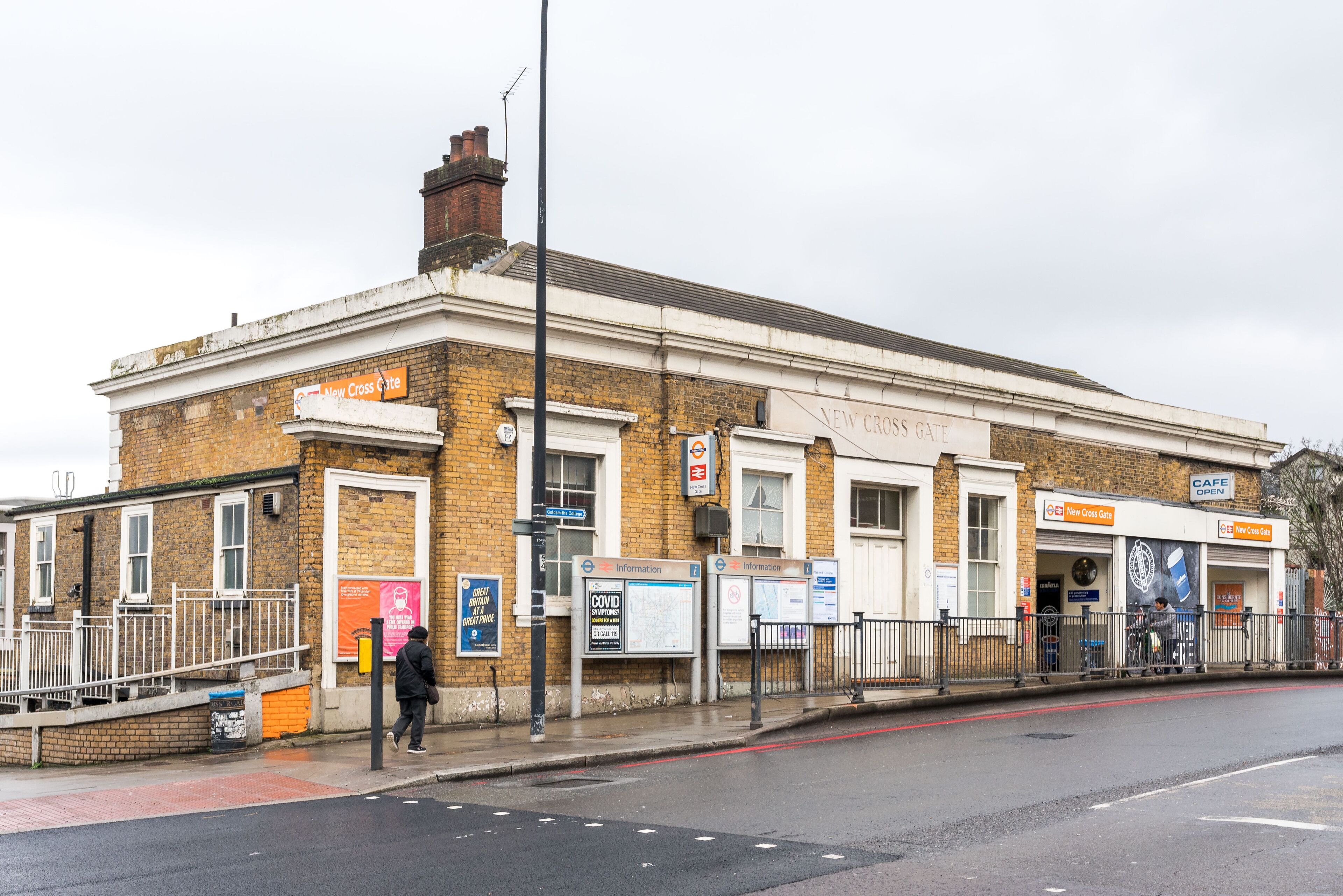 A building with a sign reading "New Cross Gate" and another sign for a cafe.