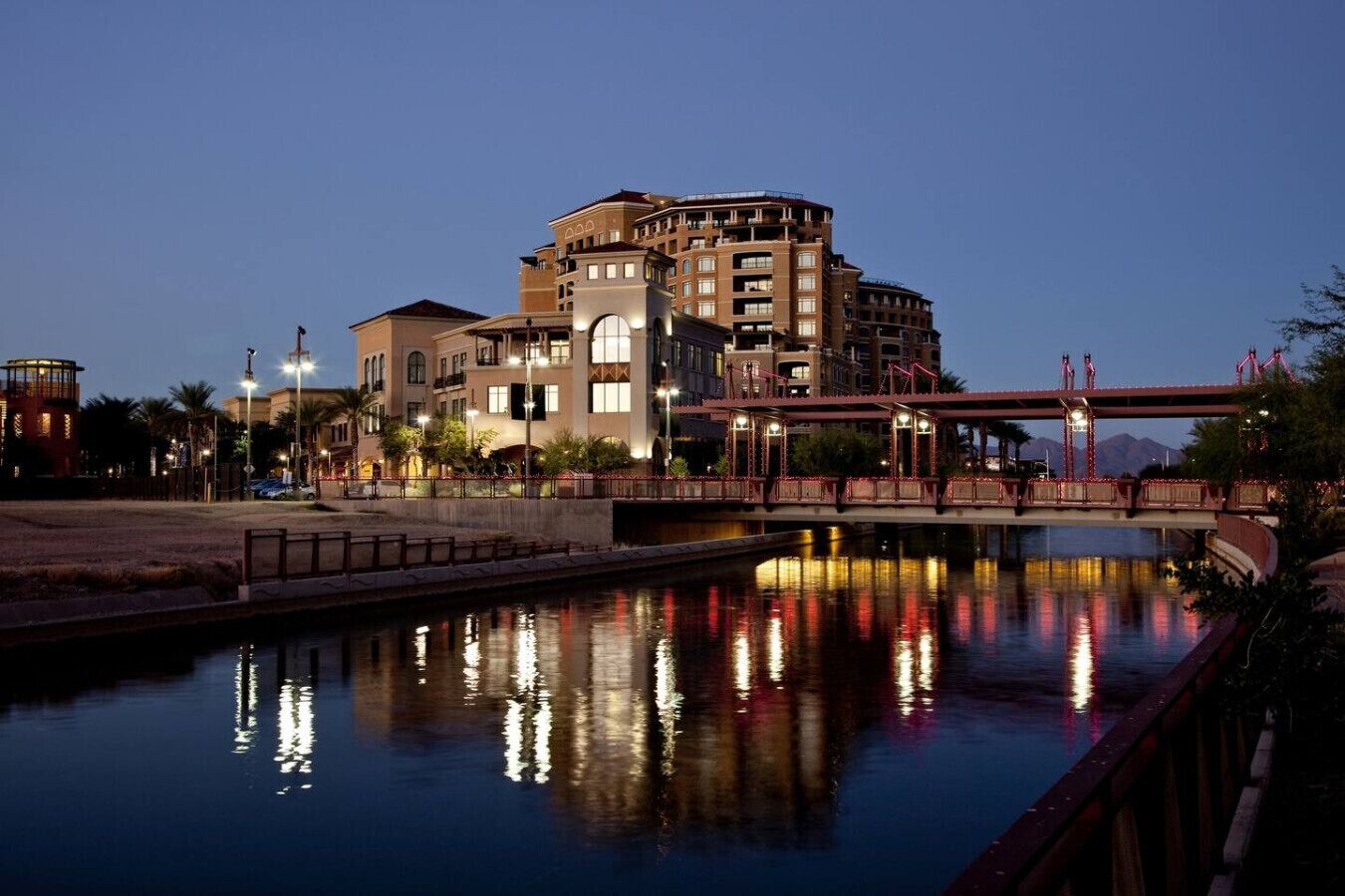 Um hotel na orla com uma ponte, com luzes refletidas na água.