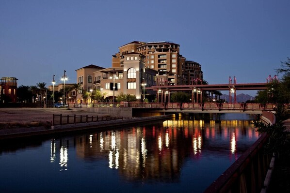 Um hotel na orla com uma ponte, com luzes refletidas na água.