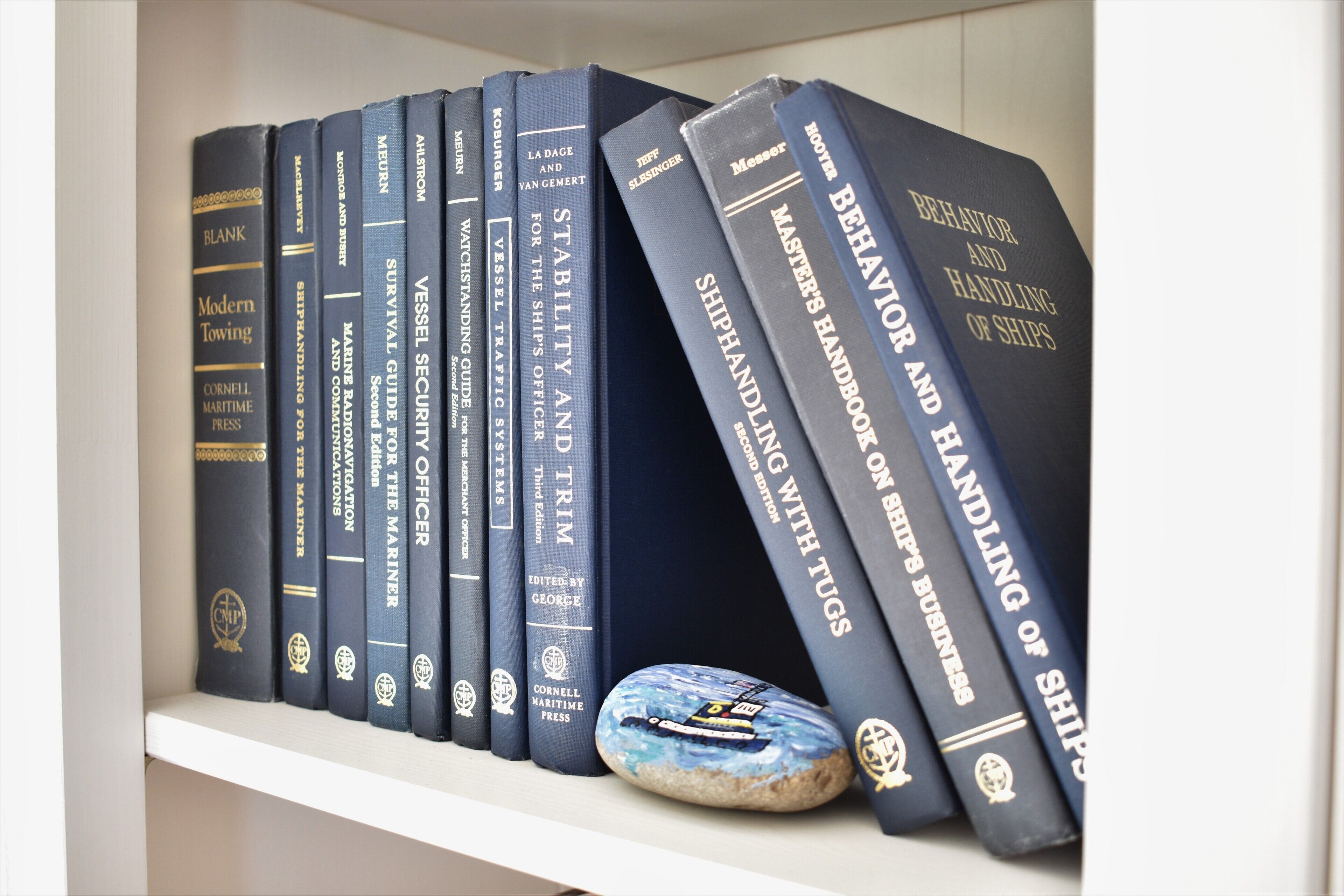 Una libreria con diversi libri su argomenti marittimi, tra cui titoli come 'Modern Towing' e 'Behavior and Handling of Ships'.