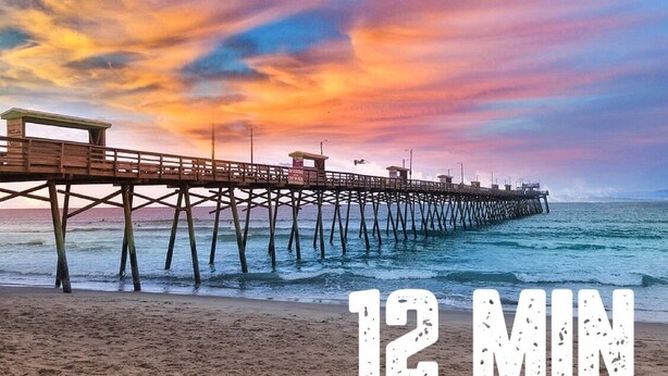 A pier extending into the ocean with a sunset in the background.