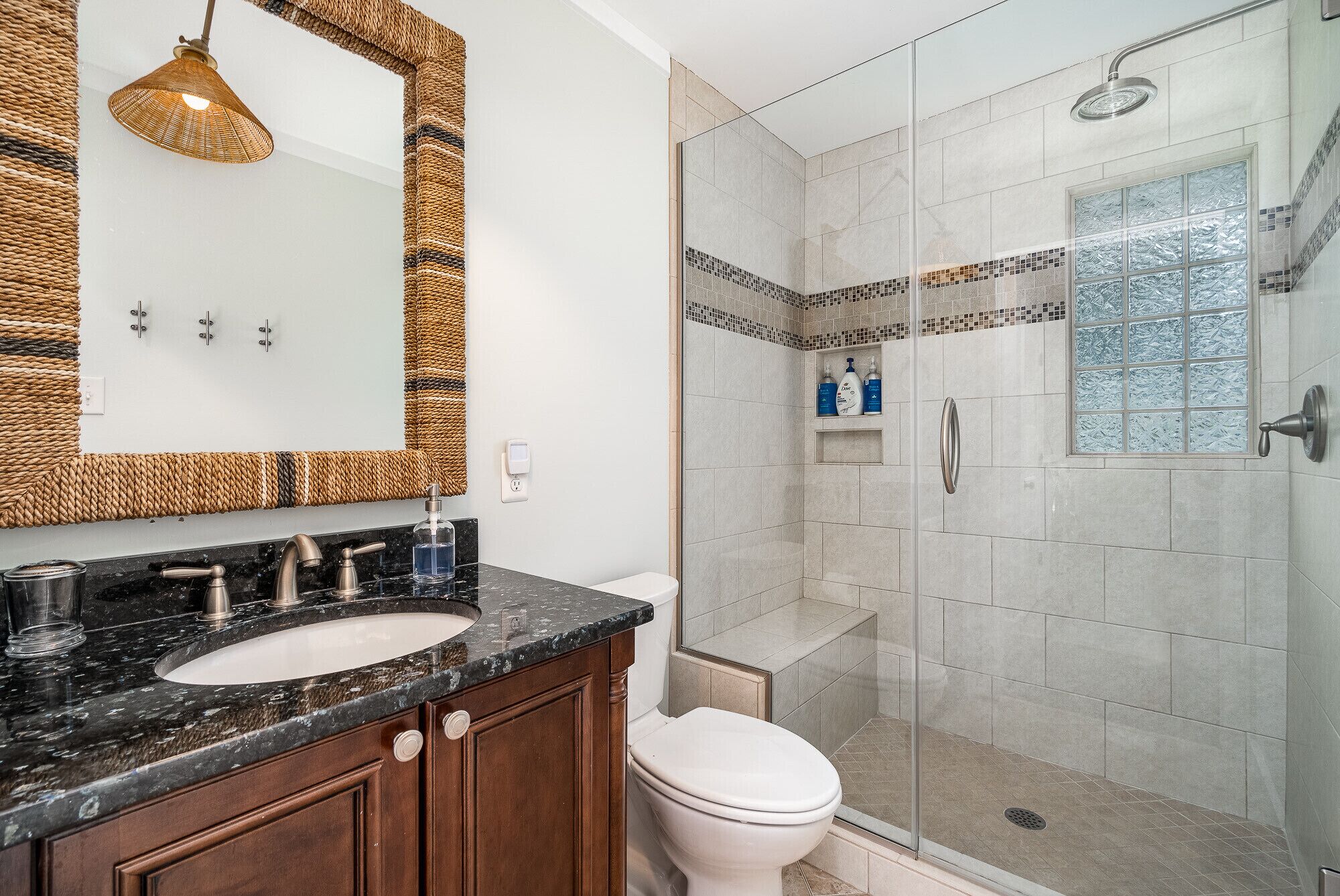 A bathroom with a large mirror, two sinks, a toilet, and a shower area.