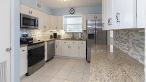 A modern kitchen with white cabinets, stainless steel appliances, and a tiled backsplash. - Spacious Townhome ~ Pet Friendly ~ Great Beach Location! (Saint Augustine)