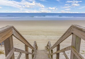Una escalera de madera que lleva a una playa con vista despejada al océano.