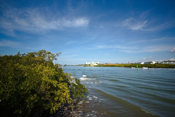 A coastal view with a building on a distant island, surrounded by greenery and calm waters.