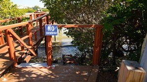 A wooden bridge with a 'NO SWIMMING' sign, leading to a body of water surrounded by trees. - Beautiful Townhome Steps from Beach (Indian Shores)