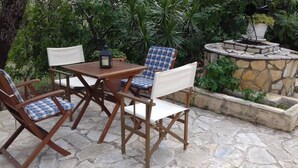 An outdoor patio with a stone table and chairs, surrounded by lush greenery. - Yria suite (Katastari, Allykes)