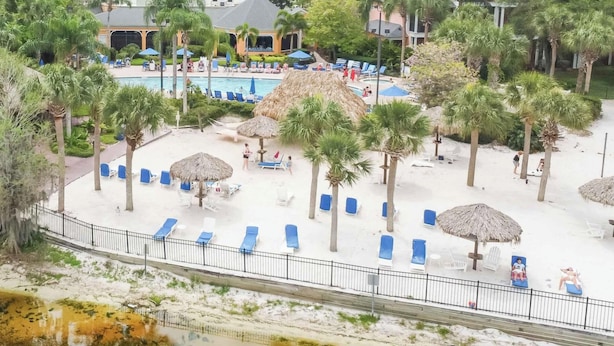 Ein Resort mit Poolbereich, Liegestühlen, Palmen und einem kleinen Gebäude.