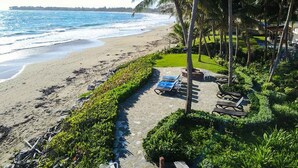 A beachside resort with a pathway leading to lounge chairs and a grassy area.