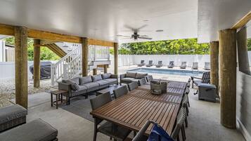 An outdoor patio with a wooden table and chairs, a sofa set, and a ceiling fan.