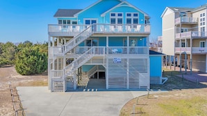 A two-story building with a blue exterior, a balcony on the upper floor, and a sign that reads "Blue Waves". - Semi-Oceanfront Dog Friendly w/ Pool, Hot Tub, Game Room, Theater, Tiki Bar (Waves)