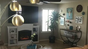 A living room with a fireplace, leather sofa, and a coffee table. - 🔥HEATED Pool, Pool Table, Golf, and Spring Training (Glendale)