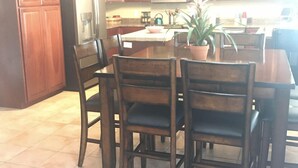 A kitchen with wooden cabinets, a microwave, a refrigerator, and a dining table with chairs. - 🔥HEATED Pool, Pool Table, Golf, and Spring Training (Glendale)