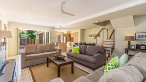 A spacious living area with a sofa set, a coffee table, and a dining area.