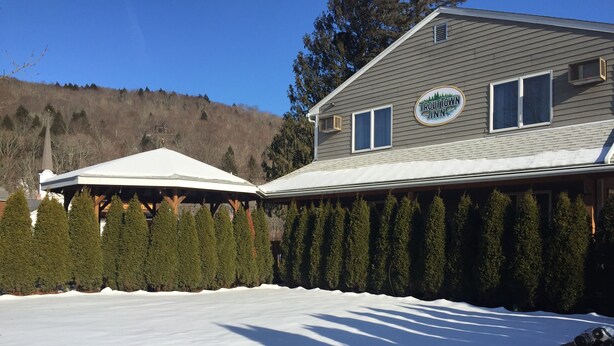 A house with a covered patio area, surrounded by snow and evergreen trees.